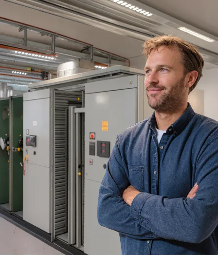 Mannelijke engineer met blauwe blouse in een technische ruimte in de opleiding Hogere installatietechniek voor elektrotechnische installaties (HIT-E) bij Habeo+.