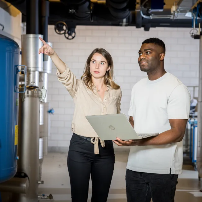 Een man en vrouw in overleg in een technische ruimte over de opleiding Technicus gebouwautomatisering bij Habeo+.
